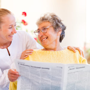 Aide_Smiling_Woman_Reading_Newspaper Aide_Smiling_Woman_Reading_Newspaper